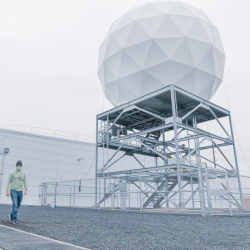 A datacenter employee walks by an orbital ground station's satellite uplink.