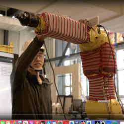 One of the researchers with a sweater-clad robot arm. 