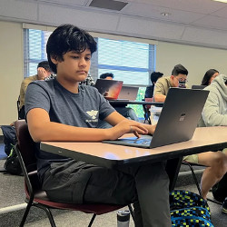 Kairan Quazi at a laptop computer in a classroom at Santa Clara University