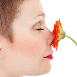 A woman smells a flower.