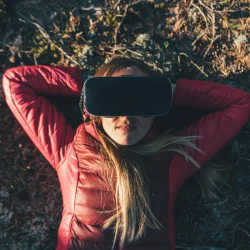 A young woman relaxes in nature, and in virtual reality.