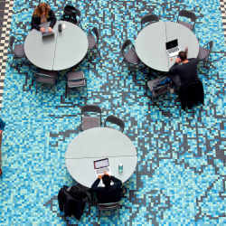 Students work on laptops above Gene Pool, a tile mosaic by Andrew Leicester inside Iowa State University's Molecular Biology Building. 