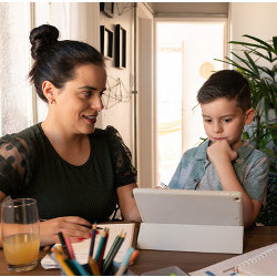 mom watches a boy doing homework on a computer