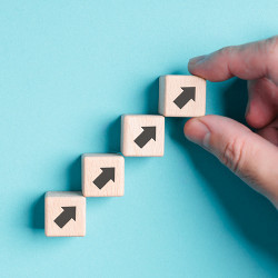 hand holds arrow-up symbol on wooden block