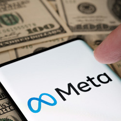 $100 bills under a smartphone displaying Meta logo