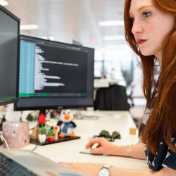 female working in front of two computer displays