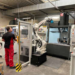 A man stands next to a robot machine at ROLEC Gehause-Systeme in Rinteln, Germany.