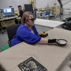 A research team member who is blind uses acoustic touch to locate and reach for an item on the table. 