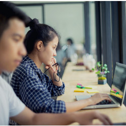 a male and female worker at laptop computers