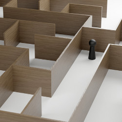 black figure inside a brown wooden maze