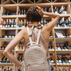 A woman tries to choose a wine to purchase.