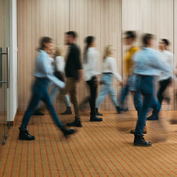 blurred crowd of individuals walking in an office building 