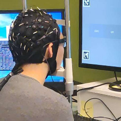 researcher wearing a sensor-filled cap looks at a display