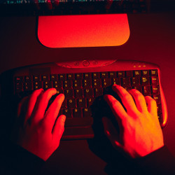 hands in red light on a computer keyboard