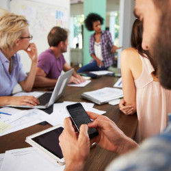 worker texting during a business meeting