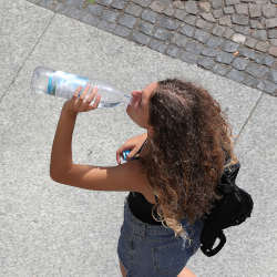 A woman drinking water from a plastic bottle.