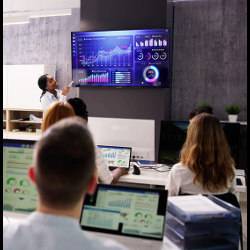 teacher looks at a large display in a college classroom with students at laptop computers