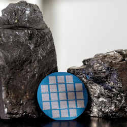 A wafer fabricated with two-dimensional carbon, flanked by two chunks of coal.
